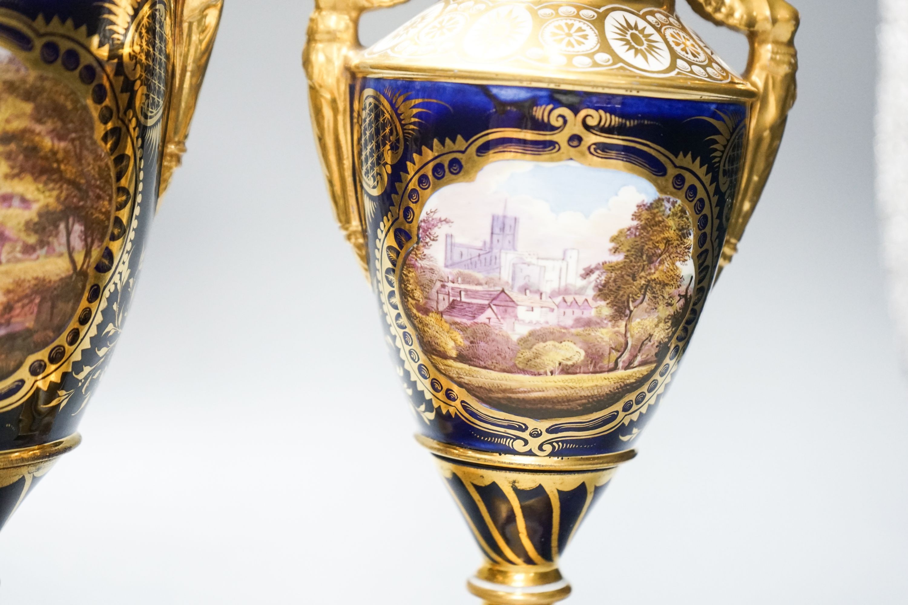 A garniture of three early 19th century English porcelain vases, c.1815-20, each painted with topographical views, tallest 26cm